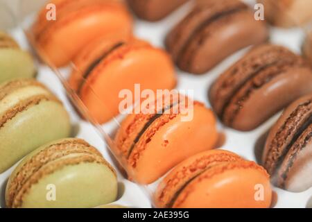 Deliziosi dolci macaron disposti in righe e colorati di amaretto dessert su sfondo bianco. -L'immagine Foto Stock