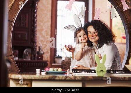 Dipinti sulle facce. Nonna e nipote hanno divertimento presso la cucina al tempo di Pasqua Foto Stock