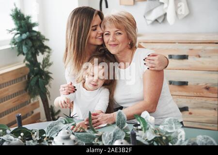 Carino abbracci. Madre, la nonna e la figlia avente un buon tempo in cucina Foto Stock