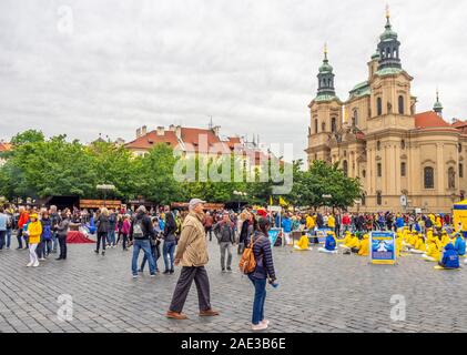 I turisti a piedi da un gruppo di Falun Dafa membri meditando e di esercitare nella città vecchia piazza con la Chiesa di San Nicola in background Praga Repubblica Ceca. Foto Stock