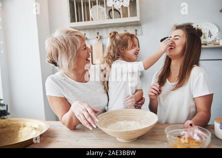 Farina sul naso. Madre, la nonna e la figlia avente un buon tempo in cucina Foto Stock