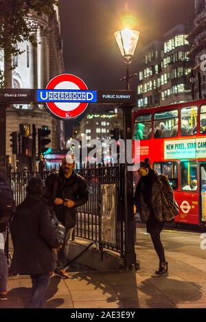 Città di Londra illuminata di notte. La gente fuori dall'ingresso alla stazione della metropolitana di Charing Cross, Trafalgar Square, Central London REGNO UNITO. Double-decker bus. Foto Stock