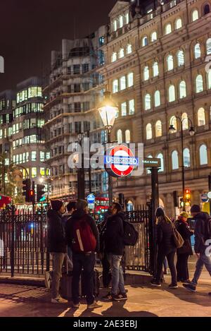 Città di Londra di notte. Le persone si sono riunite in Trafalgar Square fuori dall'ingresso passi alla stazione della metropolitana di Charing Cross in una fredda sera di novembre. Foto Stock