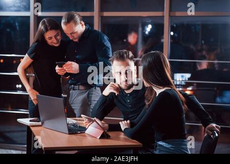 Sto ascoltando per voi. Team di giovani uomini di affari che lavora sul loro progetto di notte tempo in ufficio Foto Stock