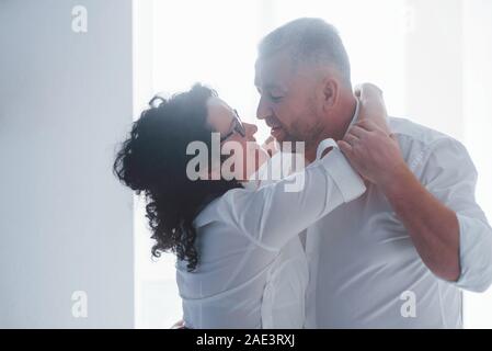 Senior l'uomo e sua moglie in maglia bianca hanno una cena romantica sulla cucina Foto Stock