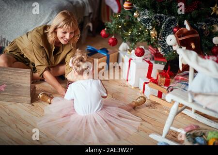 Piccoli e grandi familiari accanto a albero di Natale il divertimento Foto Stock