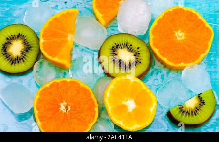 Frutta fresca di fondo. Fette di frutta fresca vista dall'alto sul ghiaccio. Fette di arance e kiwi, striscione estivo di fondo fresco Foto Stock