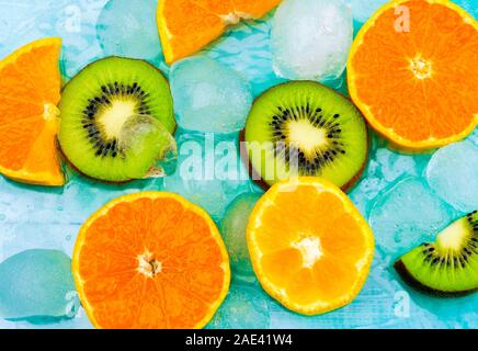 Frutta fresca di fondo. Fette di frutta fresca vista dall'alto sul ghiaccio. Fette di arance e kiwi, striscione estivo di fondo fresco Foto Stock