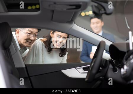 Felice Coppia matura la scelta di auto in showroom Foto Stock