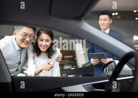 Felice Coppia matura la scelta di auto in showroom Foto Stock