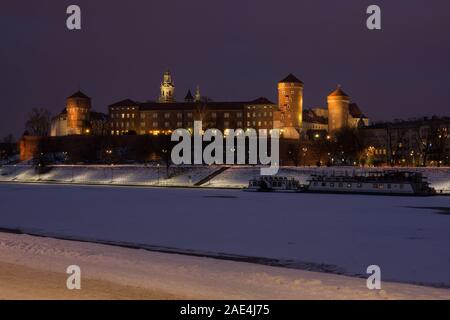 Vista notturna del centro storico castello reale di Wawel a Cracovia, Polonia, e congelati fiume Vistola durante il periodo invernale Foto Stock