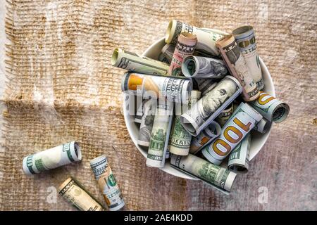 Banconote in contanti di American le fatture del dollaro di vari valori di stand sul tavolo come una metafora per mangiare i valori della vita e un promemoria della fragilità del Foto Stock