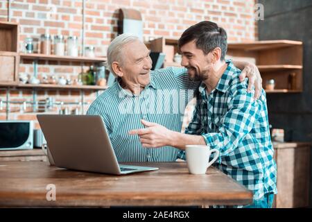 Allegro uomo anziano abbraccia il suo figlio Foto Stock