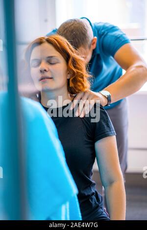 Personal trainer assiste la donna con disabilità nel suo allenamento. Sport centro riabilitativo con fisioterapisti e pazienti che lavorano insieme verso hea Foto Stock