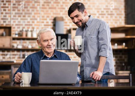 Età piacevole uomo usando il suo computer portatile Foto Stock
