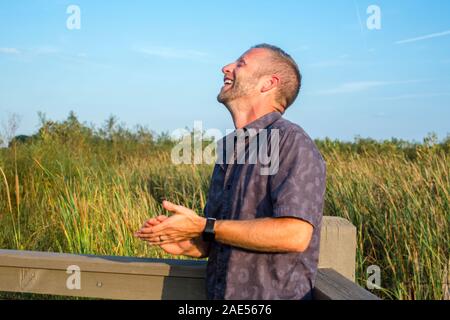 Vista laterale di un uomo gettando torna con la sua testa di risate e di gioia Foto Stock