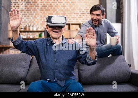 Allegro uomo anziano utilizzando il dispositivo VR Foto Stock