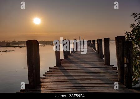 Sunrise vista lungo gli antichi di legno di teak U Bein ponte che si estende attraverso il lago Taungthaman ad Amarapura, nei pressi della città di Mandalay in Myanmar (ex Birmania chiamato) Foto Stock