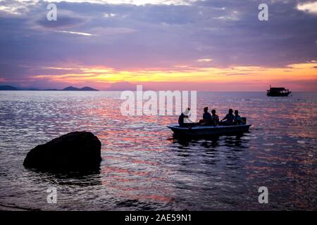 Una piccola barca di turisti si stagliano contro un rosa tramonto nel Parco Nazionale di Komodo, sull isola di Flores, Indonesia Foto Stock