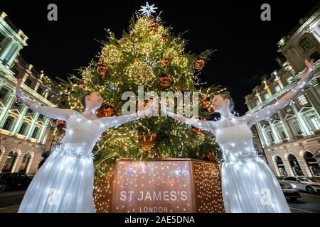 Londra, Regno Unito. 6 dicembre, 2019. Danzatori provenienti da un semaforo della Compagnia di Balletto eseguire in fairy illuminato abiti leggeri accanto a St James albero di Natale sul Lower Regent Street. Ballerini (L-R) Jasmine Cook e Amy Davies. Credito: Guy Corbishley/Alamy Live News Foto Stock