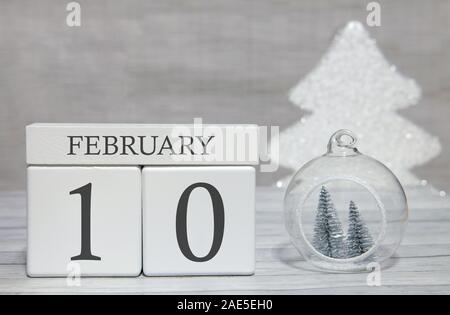 In forma di cubo il calendario per il mese di febbraio 10 su una superficie di legno e la luce dello sfondo con spazio vuoto per il testo. Foto Stock