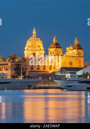 Vista del tramonto di imbarcazioni ormeggiate al fianco di edifici storici della città vecchia cinta di mura di Cartagena in Colombia.