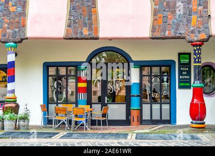 Tavolo esterno e sedie fuori di lato un negozio in Hundertwasserhaus Cittadella verde Altstadt Magdeburg Sassonia-Anhalt Germania. Foto Stock