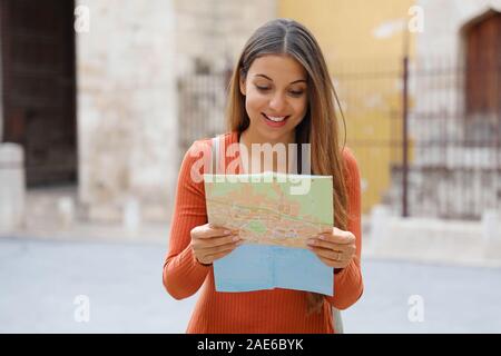 Giovane donna ricerca Direzione sulla mappa della città. Felice allegro turista femminile esplorando nuove città ricerca road o la posizione sulla mappa. Foto Stock