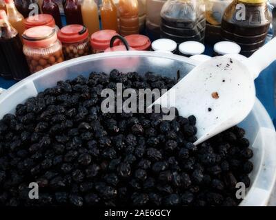 Black olive sott'aceto nel recipiente sul mercato contatore. Foto Stock