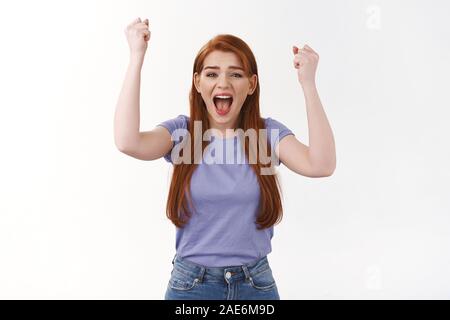 Allegro, eccitato ragazza sensazione overjoy, stringono i pugni e la pompa su di esso dal grande stupore, urlare come il tifo per la squadra, celebrare la vittoria, trionfante come Foto Stock