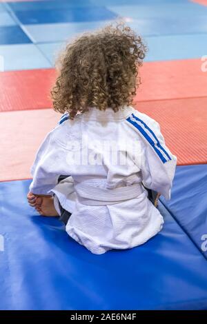 Curly ragazza si siede al Judo bambini formazione. Foto Stock