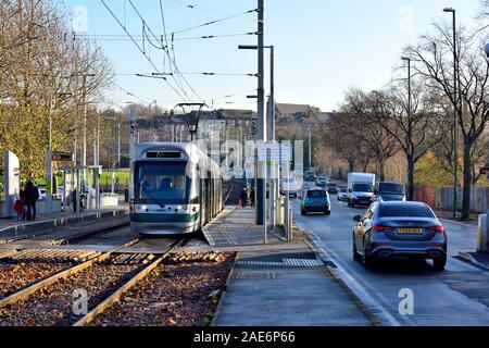 Nottingham Tram lasciando la Wilkinson street fermata del tram con il traffico sulla strada principale a Nottingham, Inghilterra ,REGNO UNITO Foto Stock