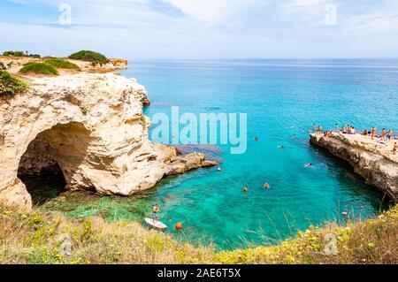 Tropea in Calabria, Italia - 09 Settembre 2019: persone diving dalla scogliera piatta, prendere il sole, nuotare nel mare cristallino dell'acqua sulla spiaggia rocciosa di Foto Stock