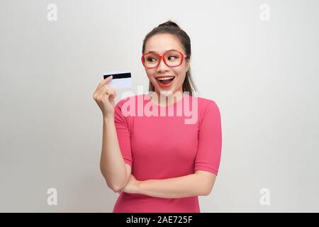 Foto di bella giovane donna isolato su sfondo bianco. Guardando la telecamera winking tenendo la carta di credito. Foto Stock