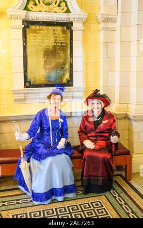 Due donne in costume, accolgono i visitatori a Dunedin stazione ferroviaria, Dunedin, Nuova Zelanda. Foto Stock