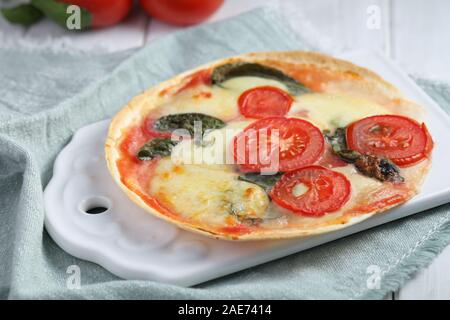 Tortilla pizza Margherita con mozzarella, pomodoro e basilico su un tavolo rustico Foto Stock