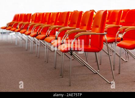 La sfocata l'immagine di sfondo di rosso fila di sedie da ufficio Foto Stock