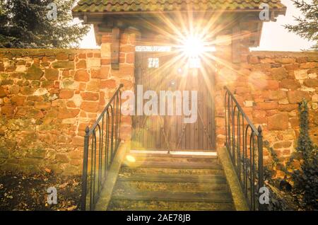 Muro di pietra con legno porta Vecchia e raggi di sole che splende attraverso. Concetto di Heaven's Gate Foto Stock