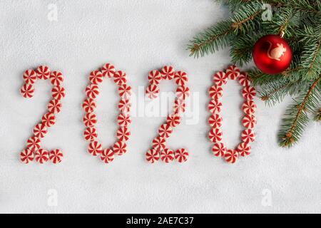 Telaio di Natale fatto di rami di abete, caramelle, sfera rossa con il simbolo del nuovo anno e decorazioni. Sfondo di natale. Sfondo 2020 isolate su Foto Stock