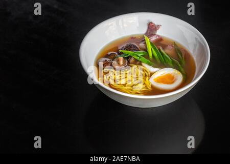 Ramen zuppa con un uovo, pasta fatta in casa, funghi e carni bovine nella piastra bianca. Foto Stock