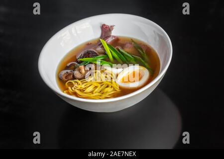 Ramen zuppa con un uovo, pasta fatta in casa, funghi e carni bovine nella piastra bianca. Foto Stock