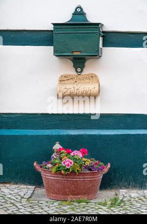 Vasca di metallo piena di fiori sotto una letterbox verde su un muro di casa con struttura in legno nella storica Altstadt Tangermünde Sassonia-Anhalt Germania Foto Stock