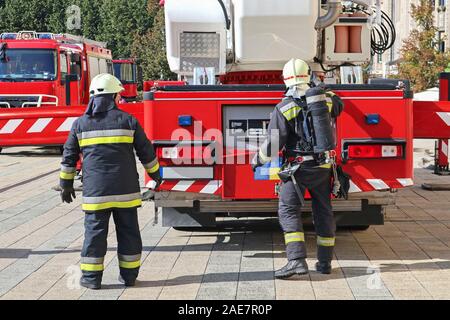 Vigili del fuoco accanto a un camion dei pompieri Foto Stock