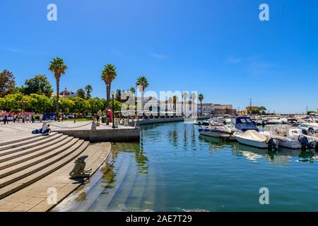 Vista attraverso il porto turistico con la statua seduto sui gradini Barche e yacht ormeggiati al porto di Faro. Faro Algarve Portogallo. Foto Stock