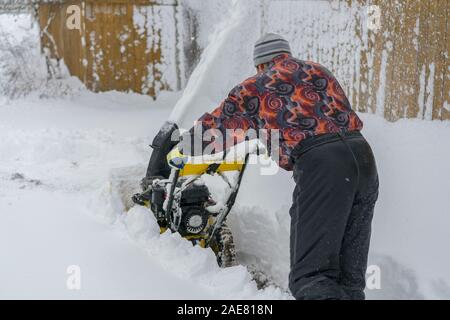 Uomo di funzionamento del ventilatore di neve per rimuovere la neve sul vialetto. Uomo che utilizza un spalaneve. Un uomo che pulisce la neve da marciapiedi con spalaneve. Foto Stock