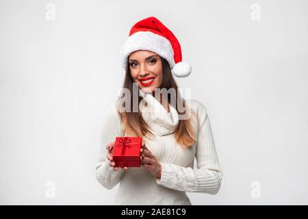 Close up ritratto bellissime caucasian woman in red Santa hat su bianco di sfondo per studio. Natale Anno Nuovo Concetto di vacanza sorpreso ragazza carina denti Foto Stock