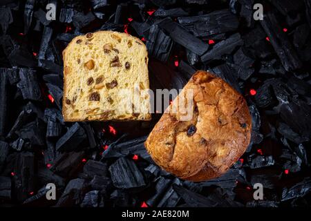 Tagliate a fette il panettone immessi sul carbone nero di sfondo sotto illuminato con luce rossa Foto Stock