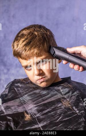 Little Boy di ottenere un taglio di capelli con una macchina da taglio Foto Stock