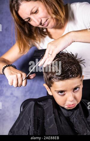 Bel ragazzo di ottenere un taglio di capelli con le forbici Foto Stock