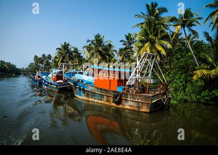 Ocean barche da pesca lungo il canale di Kerala backwaters shore con palme in una giornata di sole tra Alappuzha e Quilon, India Foto Stock